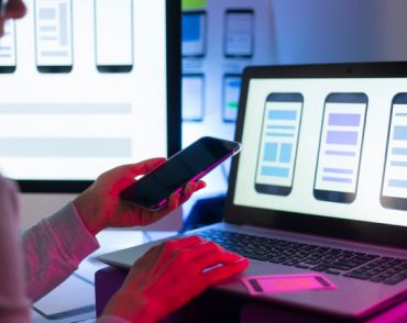 робота на ноутбуці над мобільною версією вебсайта,тримаючи смартфон в руці
